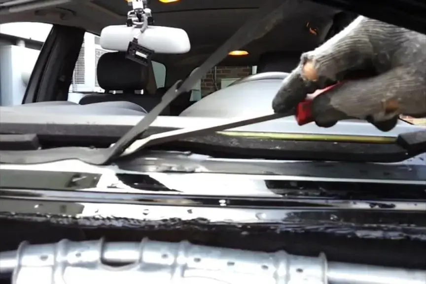 Technician cutting out a windshield seal during an auto glass replacement