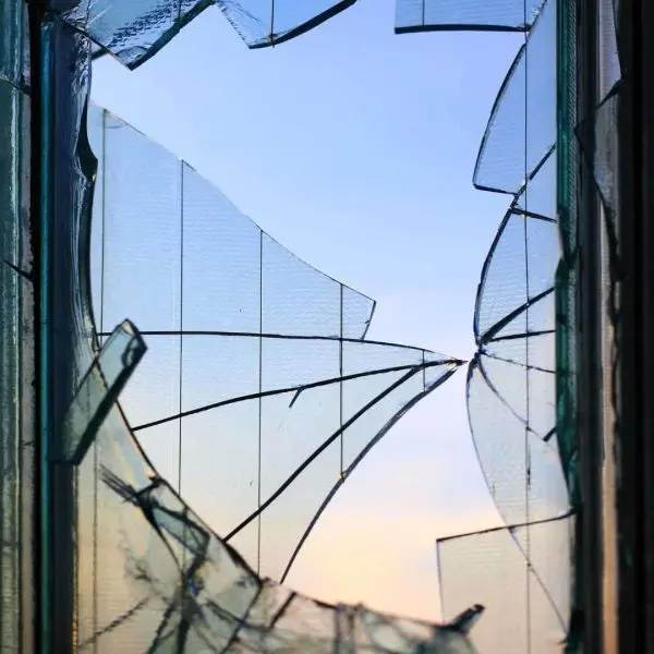 Broken glass panes in an old window frame against the sky