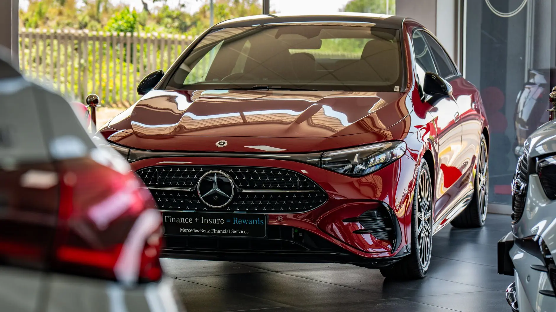 A luxurious red Mercedes-Benz displayed prominently within a car dealership showroom.