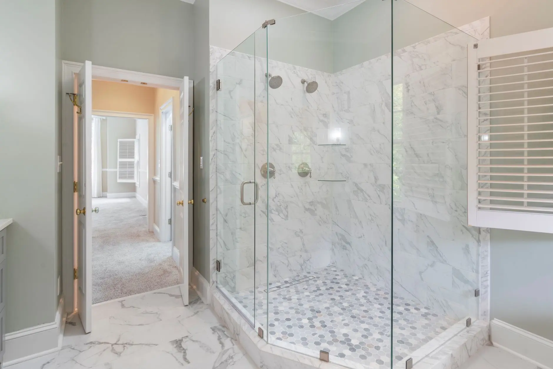 Spacious luxury bathroom featuring a contemporary marble shower with glass doors and elegant interior design.
