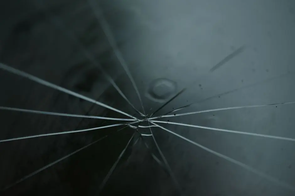 A detailed shot of cracked glass with radiating lines on a moody background.