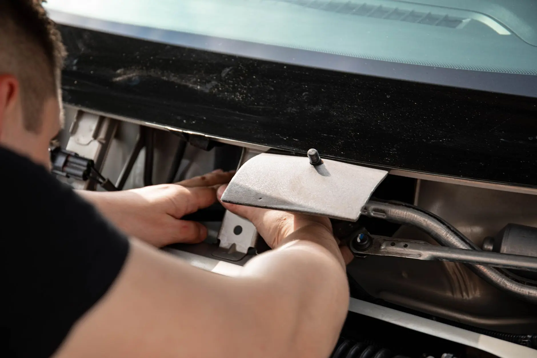 Close-up of a mechanic working on a car engine, focusing on repairs and maintenance.